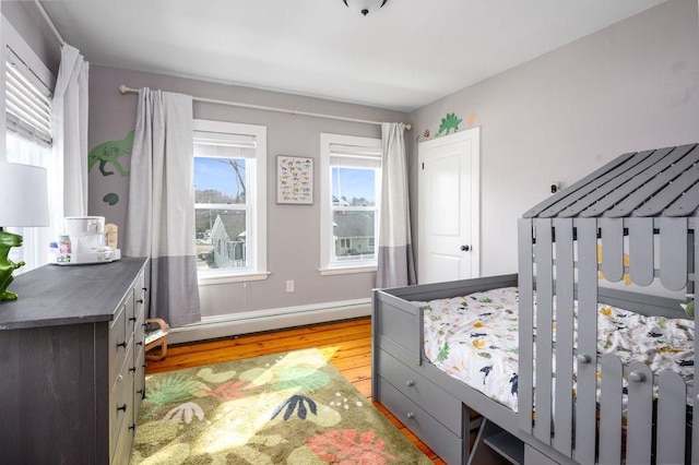 bedroom featuring baseboards, baseboard heating, and wood finished floors