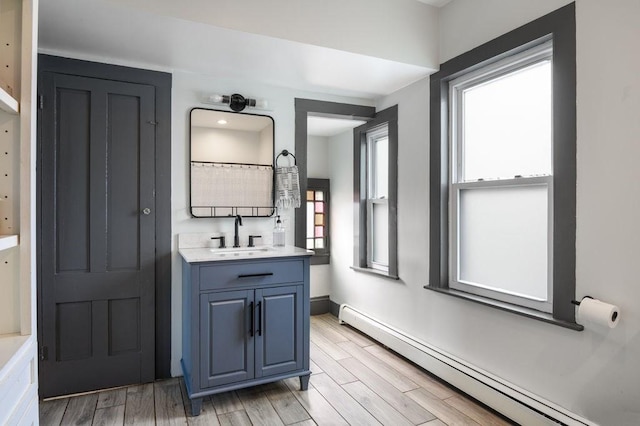 bathroom featuring baseboards, a baseboard heating unit, wood finished floors, and vanity