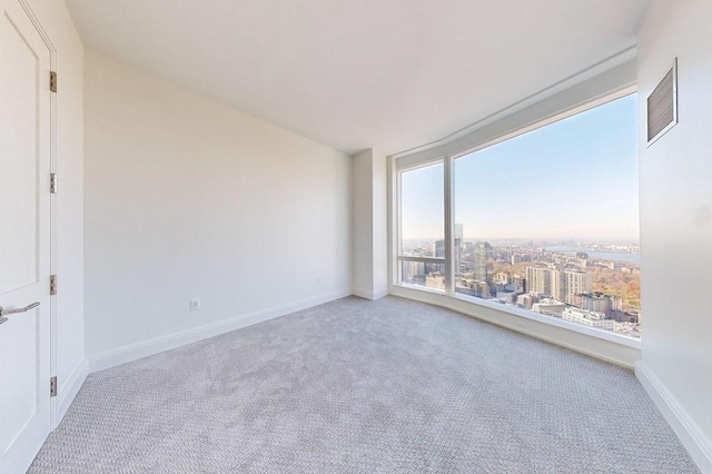 carpeted spare room with a view of city and baseboards