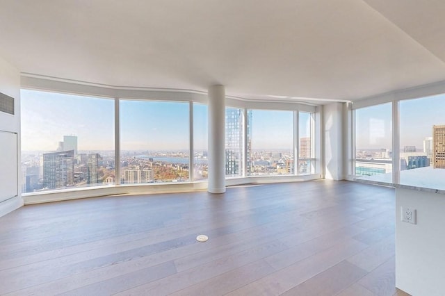 spare room featuring a city view, wood-type flooring, and expansive windows