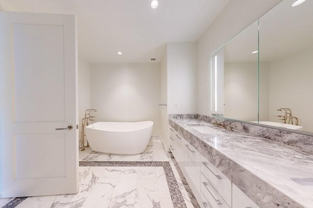 full bathroom with marble finish flooring, recessed lighting, a freestanding bath, and double vanity