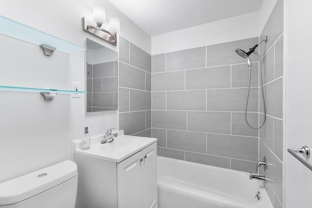 full bathroom featuring tiled shower / bath, vanity, and toilet