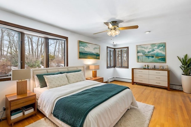 bedroom with a baseboard radiator, ceiling fan, and light wood-type flooring