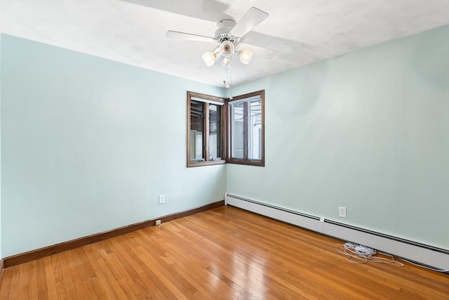 empty room featuring ceiling fan, wood-type flooring, and a baseboard heating unit