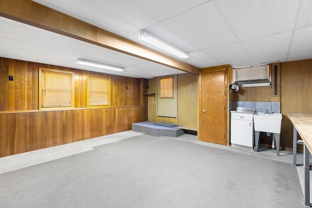 basement featuring a drop ceiling and wooden walls