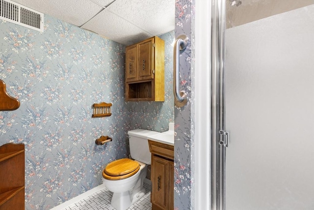 bathroom featuring tile patterned flooring, vanity, an enclosed shower, a drop ceiling, and toilet