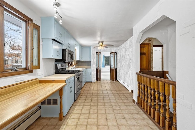 kitchen with a baseboard radiator, appliances with stainless steel finishes, blue cabinetry, and ceiling fan