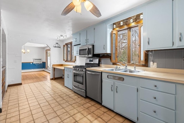 kitchen with appliances with stainless steel finishes, an AC wall unit, tasteful backsplash, sink, and ceiling fan