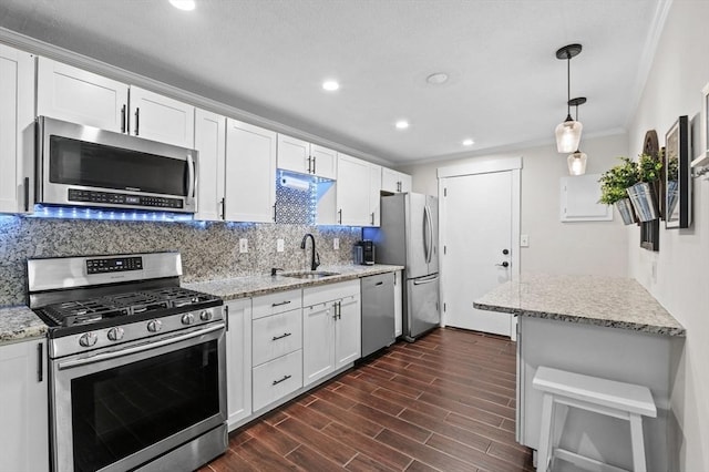 kitchen with sink, white cabinetry, decorative light fixtures, stainless steel appliances, and backsplash