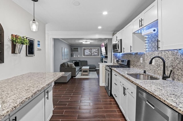 kitchen featuring appliances with stainless steel finishes, sink, pendant lighting, and white cabinets