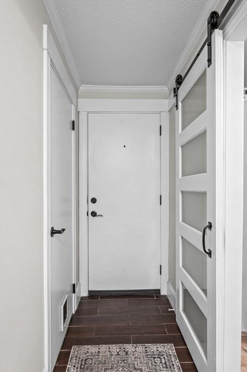 doorway with ornamental molding, a barn door, and a textured ceiling