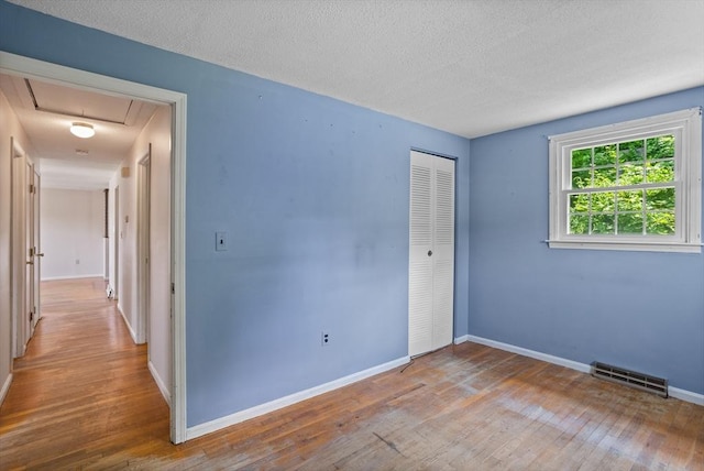16 Winding Ln, Lowell, MA 01852 - unfurnished bedroom with wood finished floors, attic access, a closet, and a textured ceiling