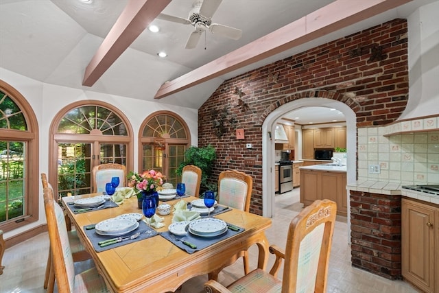 dining area featuring lofted ceiling with beams, brick wall, and ceiling fan