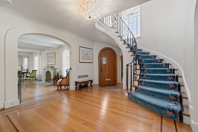 entrance foyer with crown molding, a healthy amount of sunlight, beamed ceiling, and light hardwood / wood-style floors