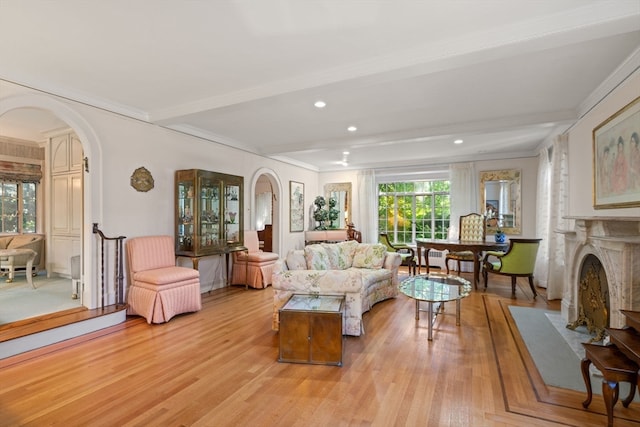 living room featuring plenty of natural light, ornamental molding, beam ceiling, and light hardwood / wood-style floors