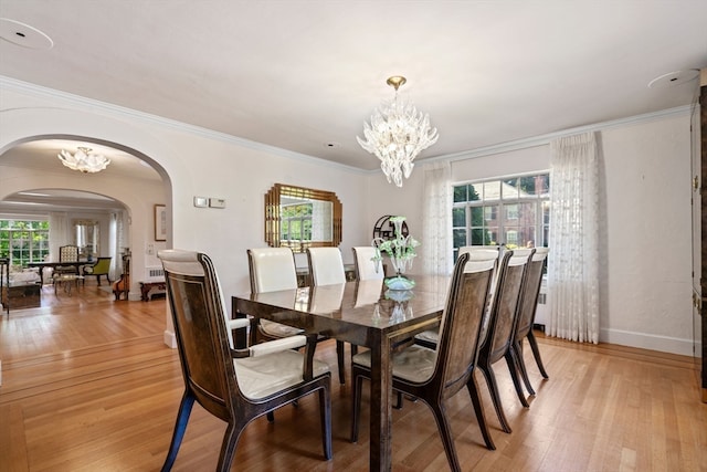 dining area with crown molding, an inviting chandelier, and light hardwood / wood-style floors