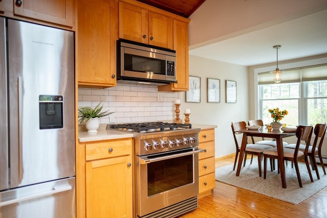 11 Cliff St, Dennis, MA 02638 - kitchen with stainless steel appliances, tasteful backsplash, light wood-style floors, light countertops, and hanging light fixtures