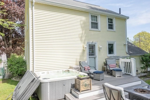 back of property featuring a fire pit, a hot tub, and a deck