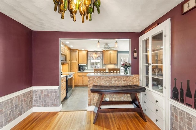 kitchen featuring light hardwood / wood-style flooring, appliances with stainless steel finishes, an inviting chandelier, and light brown cabinets