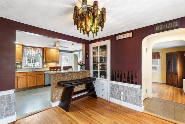 kitchen with dishwasher, light hardwood / wood-style floors, sink, kitchen peninsula, and a breakfast bar