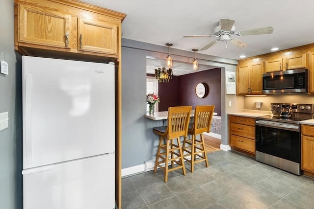 kitchen with ceiling fan, a kitchen breakfast bar, hanging light fixtures, and appliances with stainless steel finishes