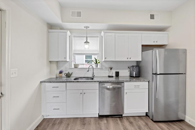 10 Elliott Pl Unit 3F, Peabody, MA 01960 - kitchen with appliances with stainless steel finishes, white cabinetry, light wood finished floors, stone counters, and decorative backsplash
