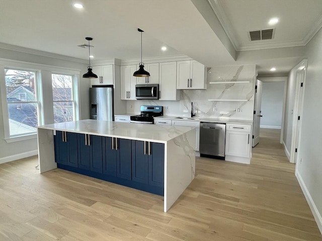 kitchen featuring white cabinetry, sink, stainless steel appliances, pendant lighting, and a kitchen island