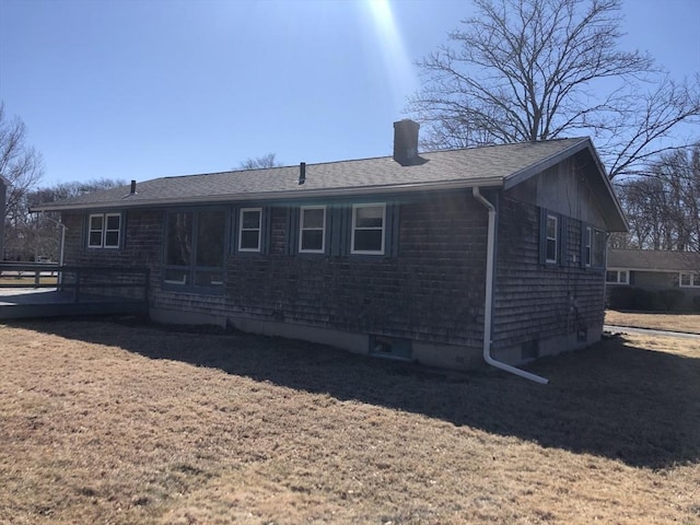 rear view of property featuring a deck, a yard, a shingled roof, and a chimney