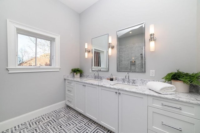 bathroom featuring double vanity, baseboards, a sink, and tiled shower