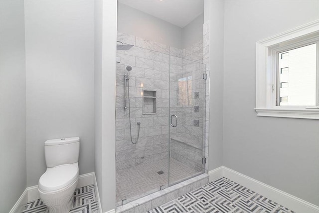 full bath with a stall shower, toilet, and baseboards