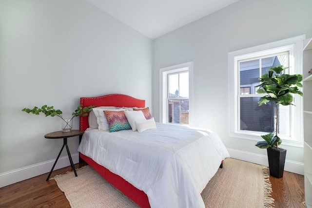 bedroom with lofted ceiling, baseboards, and wood finished floors