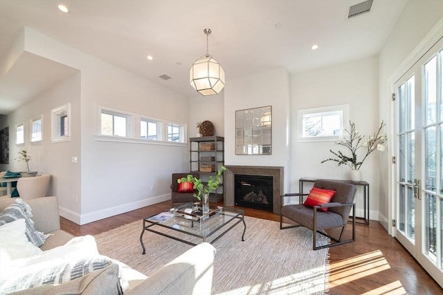 living area with wood finished floors, a glass covered fireplace, visible vents, and baseboards