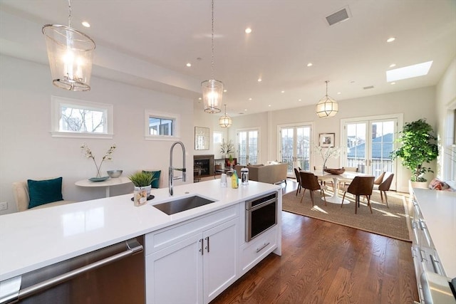 kitchen with dark wood finished floors, light countertops, a sink, and stainless steel dishwasher