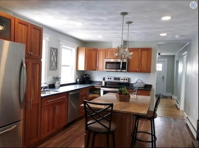 kitchen featuring a baseboard heating unit, stainless steel appliances, a breakfast bar, and dark wood-style flooring