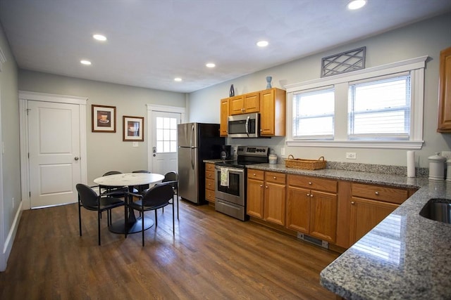 kitchen featuring stainless steel appliances, brown cabinetry, visible vents, and dark wood finished floors