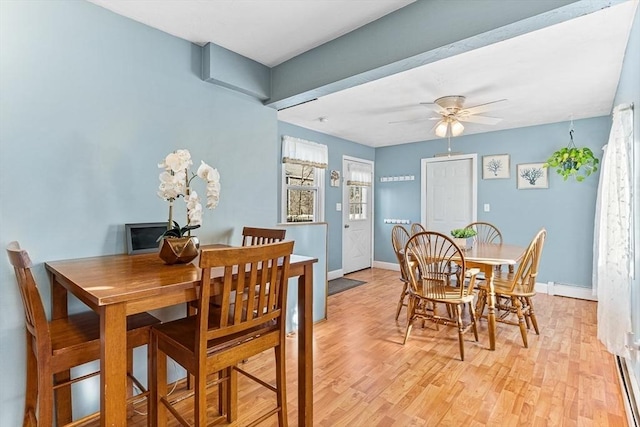 dining space with baseboards, a baseboard radiator, light wood-type flooring, and ceiling fan
