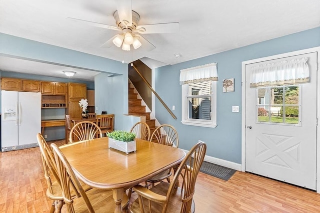 dining space with stairway, baseboards, ceiling fan, and light wood-style flooring