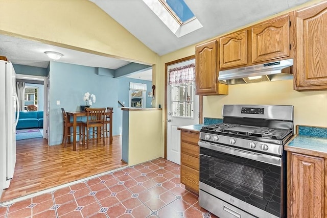kitchen featuring stainless steel range with gas cooktop, freestanding refrigerator, under cabinet range hood, and a healthy amount of sunlight