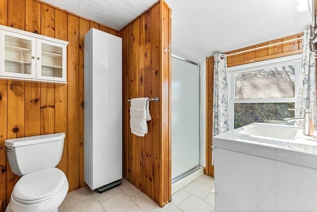bathroom with tile patterned flooring, a shower stall, wood walls, and toilet