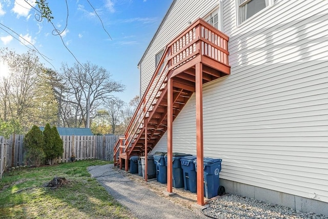 view of side of property featuring a lawn, fence, a wooden deck, and stairs