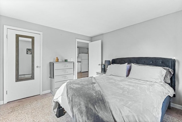 carpeted bedroom with freestanding refrigerator and baseboards