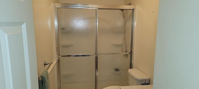 full bath with toilet and a stall shower