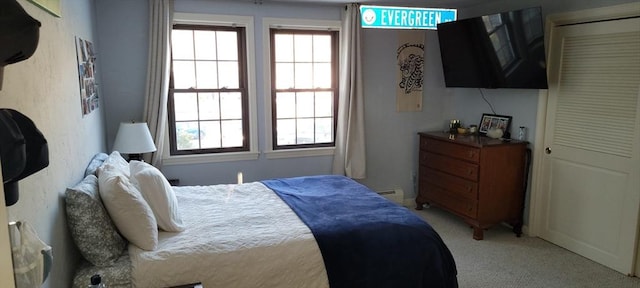bedroom with light carpet, multiple windows, and a baseboard heating unit