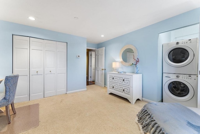 laundry room featuring stacked washer / dryer and light carpet