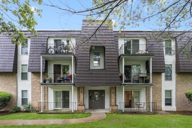 18 Shadowbrook Ln Unit 40, Milford, MA 01757 - view of property featuring a balcony, a front yard, mansard roof, and brick siding