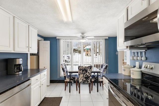 kitchen with dark countertops, appliances with stainless steel finishes, a ceiling fan, white cabinets, and a textured ceiling