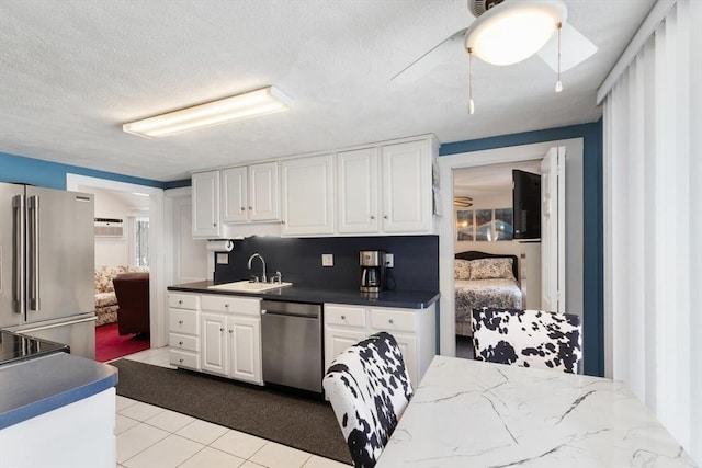 kitchen featuring a textured ceiling, stainless steel appliances, a sink, white cabinets, and tasteful backsplash