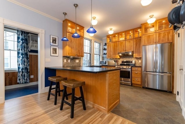 kitchen featuring appliances with stainless steel finishes, decorative backsplash, hanging light fixtures, kitchen peninsula, and a breakfast bar area