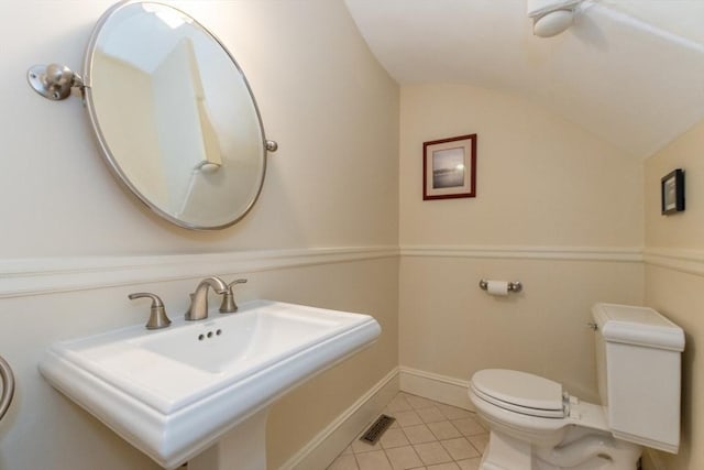 bathroom with toilet, tile patterned flooring, vaulted ceiling, and sink