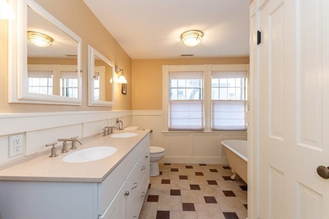 bathroom with a bathtub, vanity, and toilet